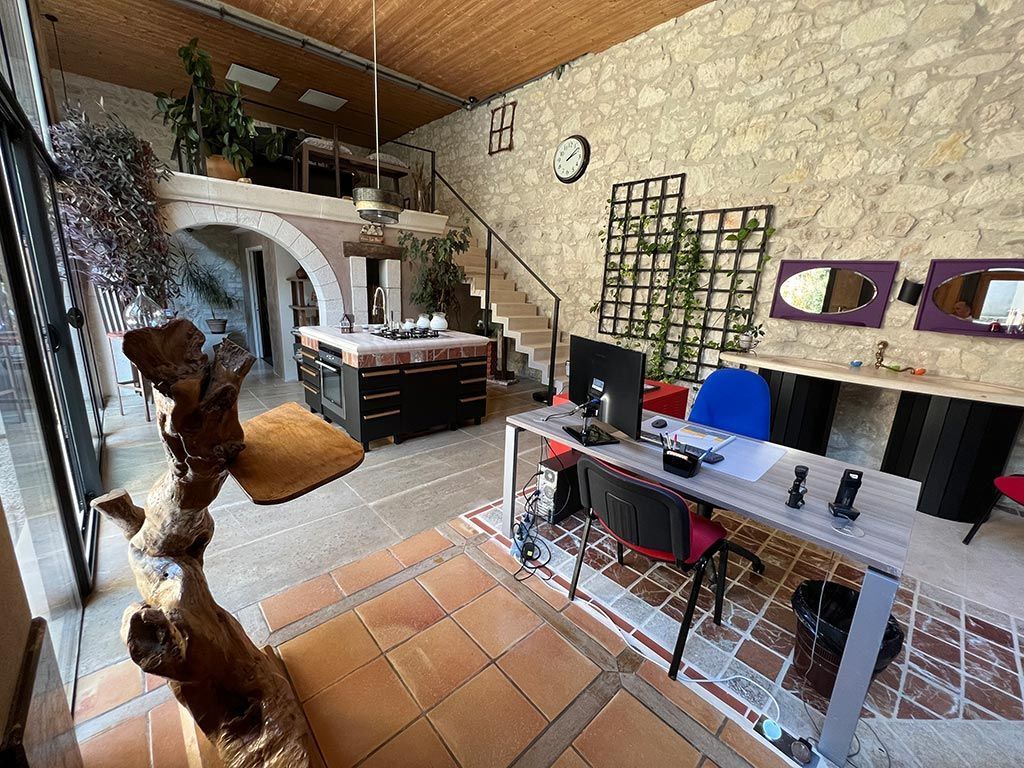 Intérieur de bureau avec un bureau, un mur en pierre, des escaliers et un petit balcon.