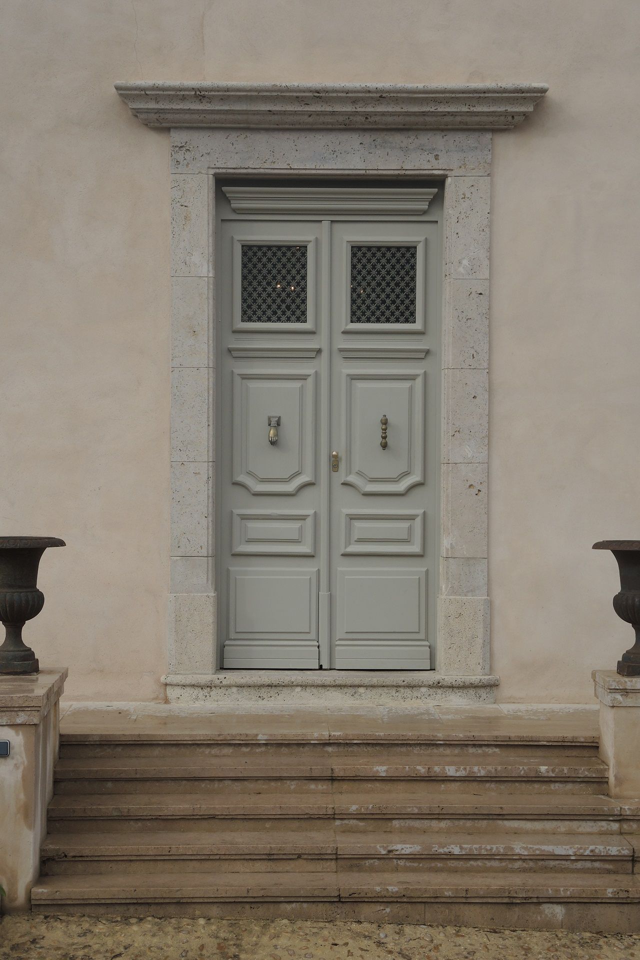 Portes doubles gris clair avec cadre et marches en pierre.
