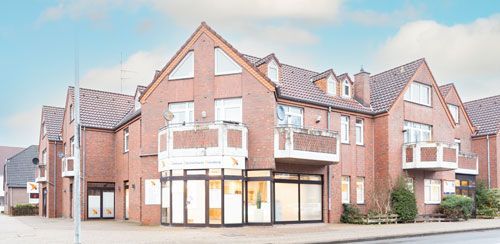 Backstein-Wohnhaus mit Geschäften im Erdgeschoss und Balkonen darüber