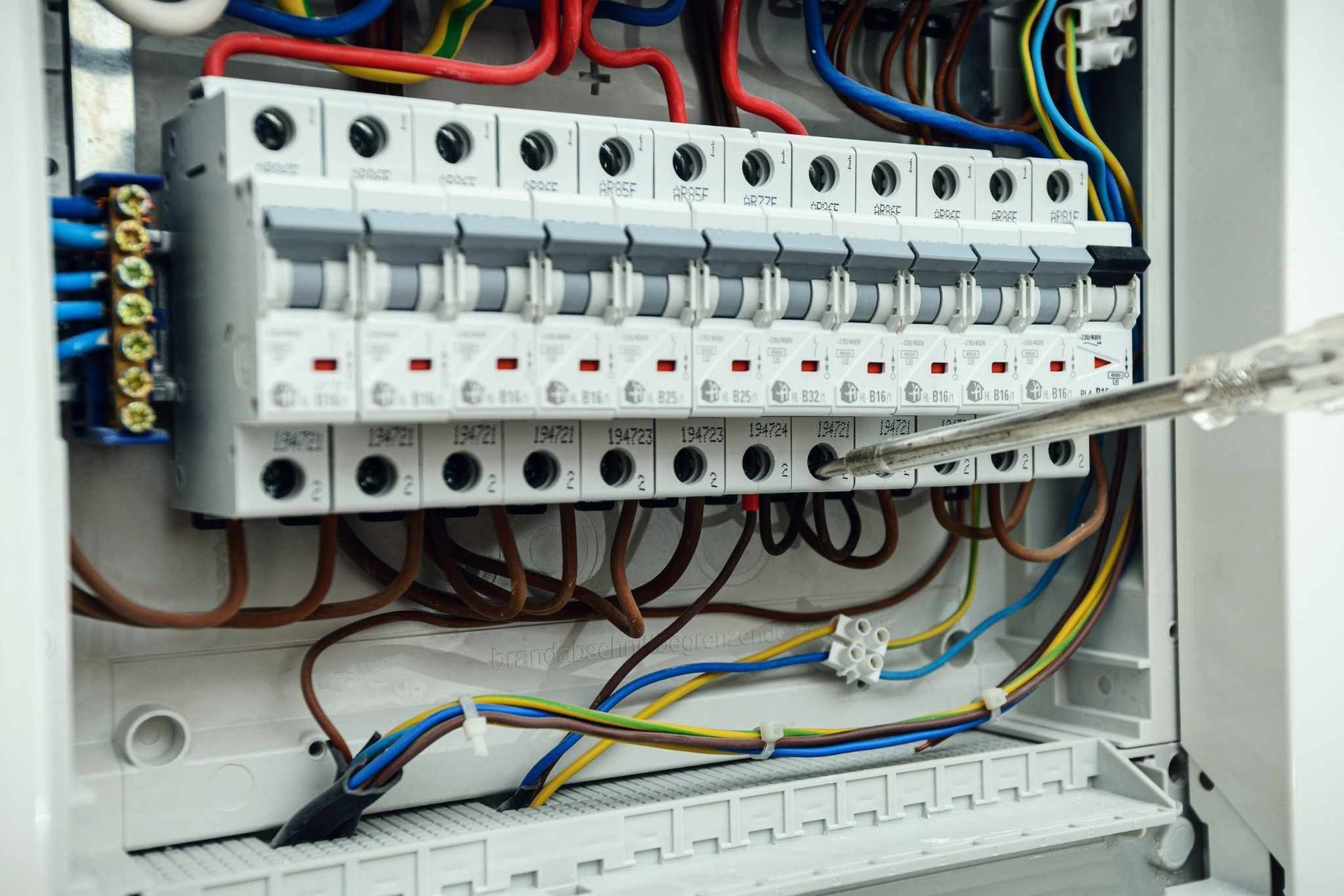 Panel de control eléctrico abierto con filas de disyuntores y cableado multicolor.