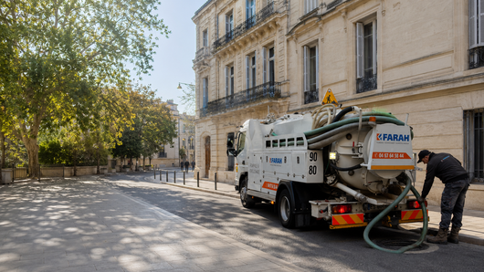 Personne qui contrôle les canalisations avec en fond un véhicule de l'entreprise.