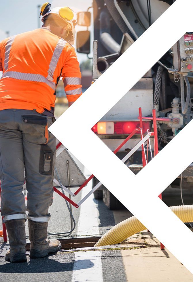 Ouvrier en tenue de sécurité orange debout à côté d'un camion-malaxeur à béton sur un chantier de construction.