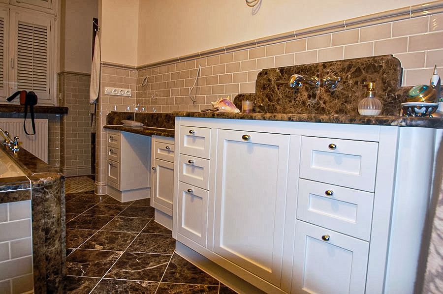 Sanitärmöbel mit einer marmorierten Steinplatte und weißen Holzschränken