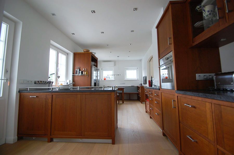 Dunkelbraune Küche aus Holz mit Anthrazitfarbener Arbeitsfläche und Theke als Raumtrenner
