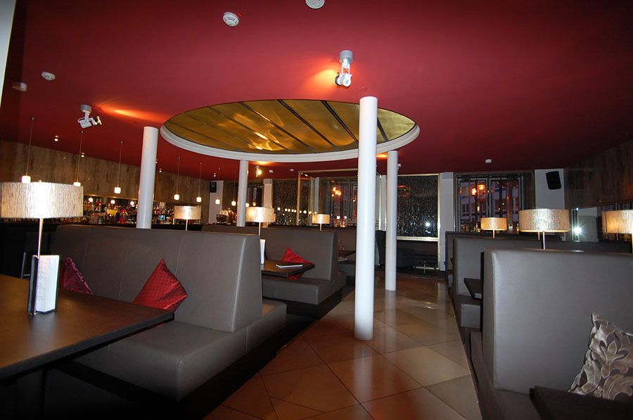 Restaurant Innenraum mit Holzdecke und -boden, Tischen und Stühlen und einem Bedientresen. Alles aus Holz