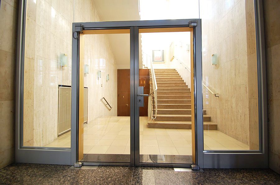 Eingangstür aus Glas und Metallrahmen mit Glasumrandung