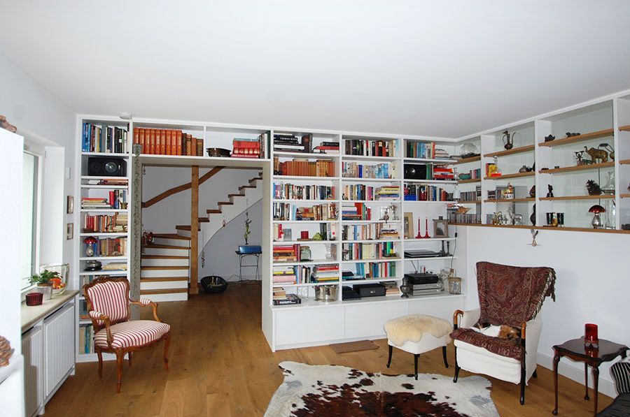 Eingebaute Regalwand die über dem Durchgang verläuft und die Wand entlang mit vielen Büchern