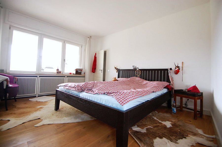 Bett aus dunklem fast schwarzen Holz mit rot karierten Bettbezug