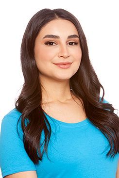 Eine Frau mit langen dunklen Haaren trägt ein blaues Hemd und lächelt.