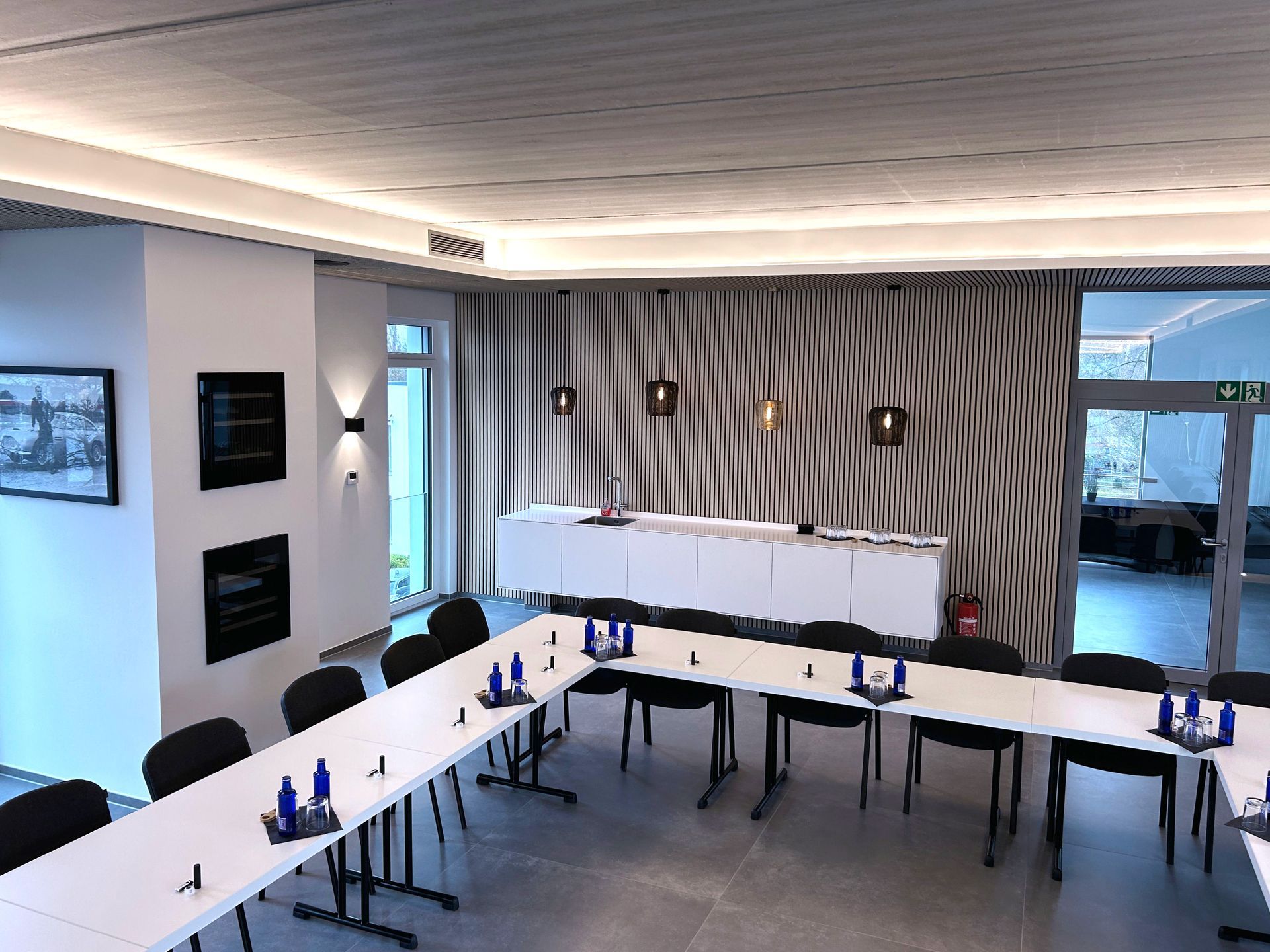 Konferenzraum mit langen Tischen, Stühlen und abstrakter Wandkunst.