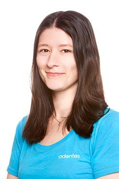 Eine Frau mit langen Haaren trägt ein blaues Hemd und lächelt.