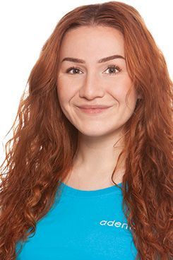 Zahnmedizinische Fachangestellte Aida Eine Frau mit langen Haaren trägt ein blaues Hemd und lächelt.