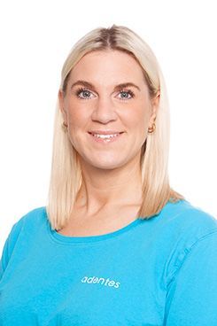 Dental Hygienist Jessica Eine Frau trägt ein blaues Poloshirt und lächelt.