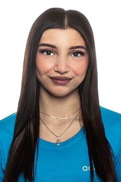 Unsere Assistenz Team Eine Frau mit langen Haaren trägt ein blaues Hemd und eine Halskette.