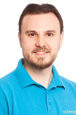 TSP Implantologie Ein Mann in einem blauen Poloshirt lächelt in die Kamera.