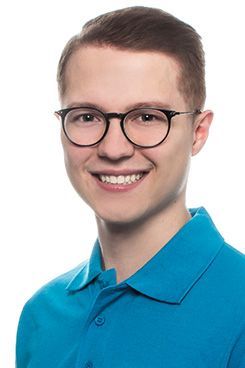 Zahnärztin Kiana Ein junger Mann mit Brille und blauem Hemd lächelt in die Kamera.