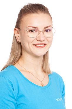 Eine Frau mit langen Haaren trägt ein blaues Hemd und lächelt.