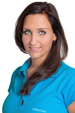 Rezeptionistin Nicole Die Frau trägt ein blaues Hemd und lächelt in die Kamera.