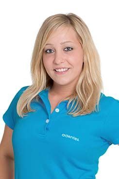 Eine Frau trägt ein blaues Poloshirt und lächelt.
