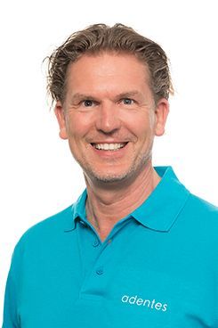 Zahnarzt Martin Sperling Ein Mann in einem blauen Poloshirt lächelt in die Kamera.