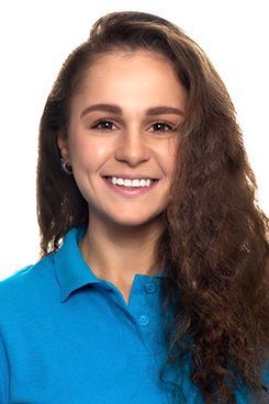 Zahnarzt Assistenz Jennifer Die Frau trägt ein blaues Poloshirt und lächelt in die Kamera.