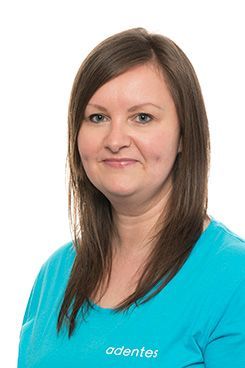 Verwaltungsangestellte Birgit Eine Frau trägt ein blaues Hemd und lächelt in die Kamera.