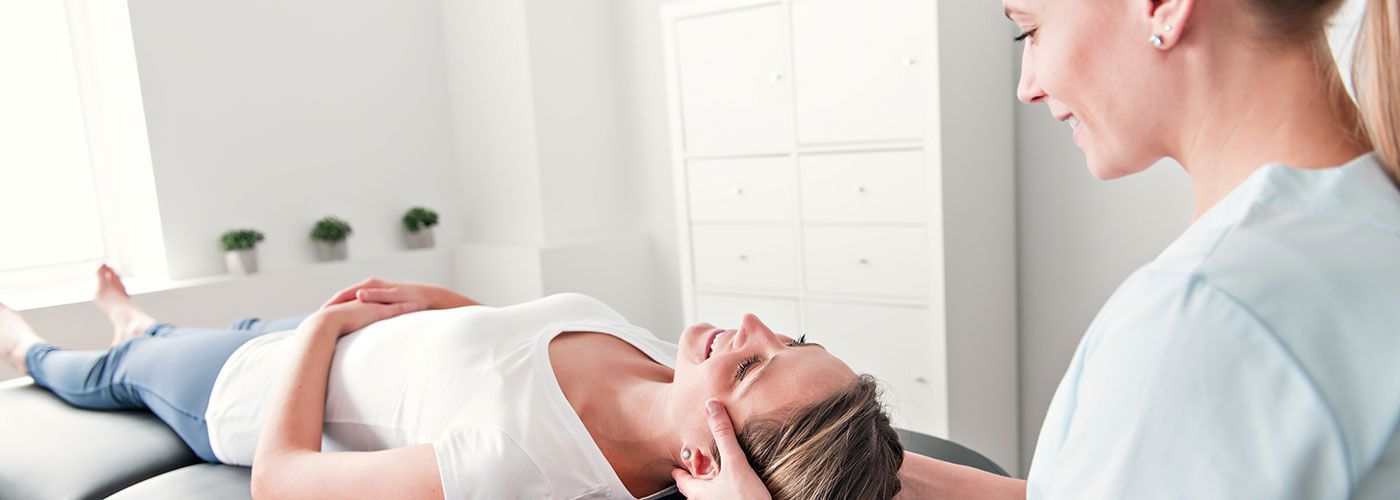 Physio von adentes: Medizinisches Versorgungszentrum in St. Augustin Eine Frau liegt auf einem Tisch und wird von einer Krankenschwester massiert.