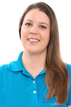 Unser Verwaltungsteam Eine Frau trägt ein blaues Poloshirt und lächelt.