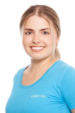 Eine Frau mit langen blonden Haaren trägt ein blaues Hemd und lächelt.
