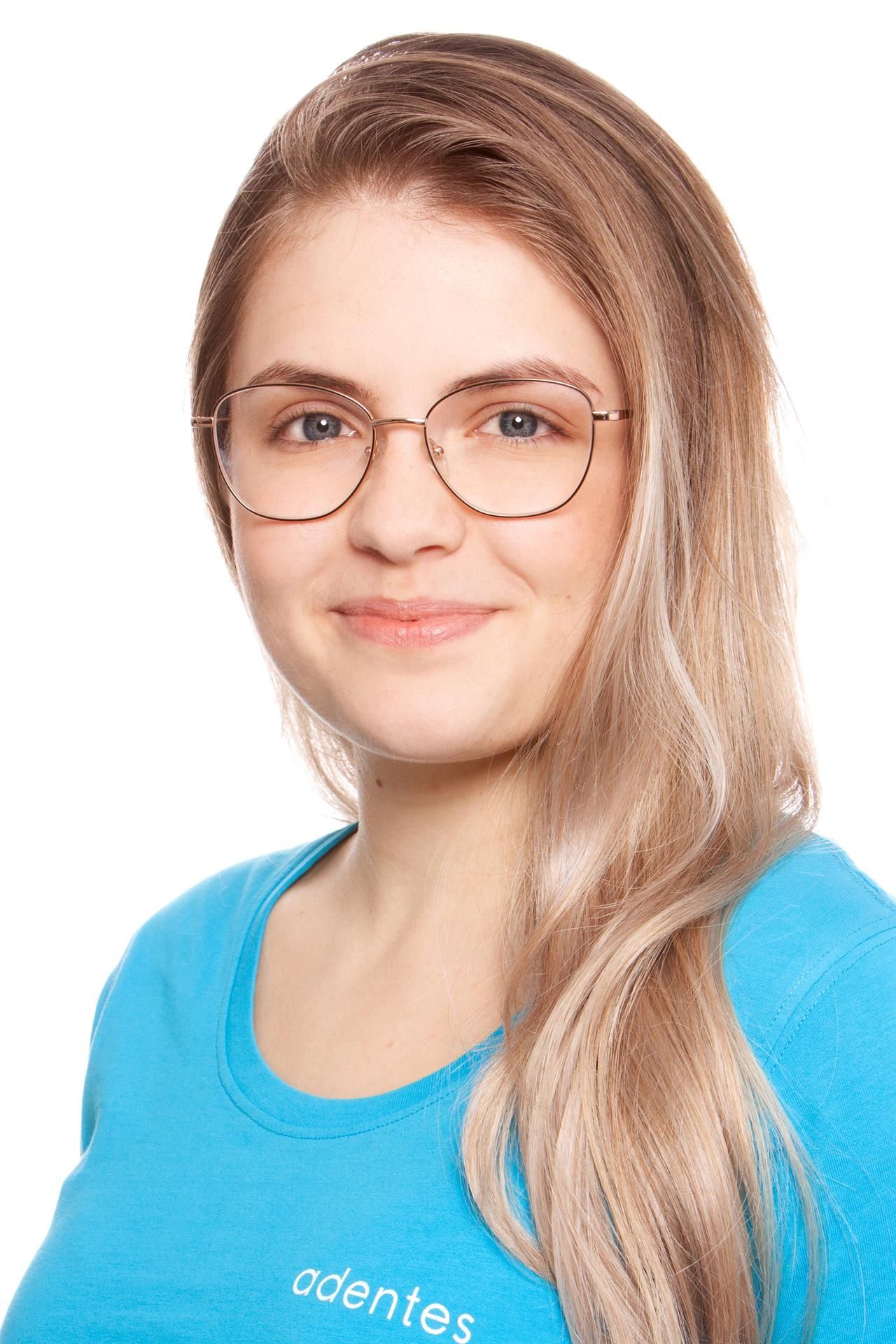Rezeptionistin Christina Eine Frau mit Brille und blauem Hemd lächelt in die Kamera.