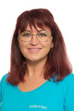 Zahnarzt Assistenz Jennifer Eine Frau mit roten Haaren und Brille trägt ein blaues Hemd und lächelt.