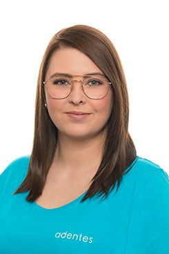 Rezeptionistin Christina Eine Frau mit Brille und blauem Hemd lächelt in die Kamera.