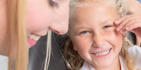 Eine Frau und ein kleines Mädchen lächeln und schauen einander an.