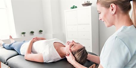 Eine Frau liegt auf einem Tisch und wird von einer Krankenschwester massiert.