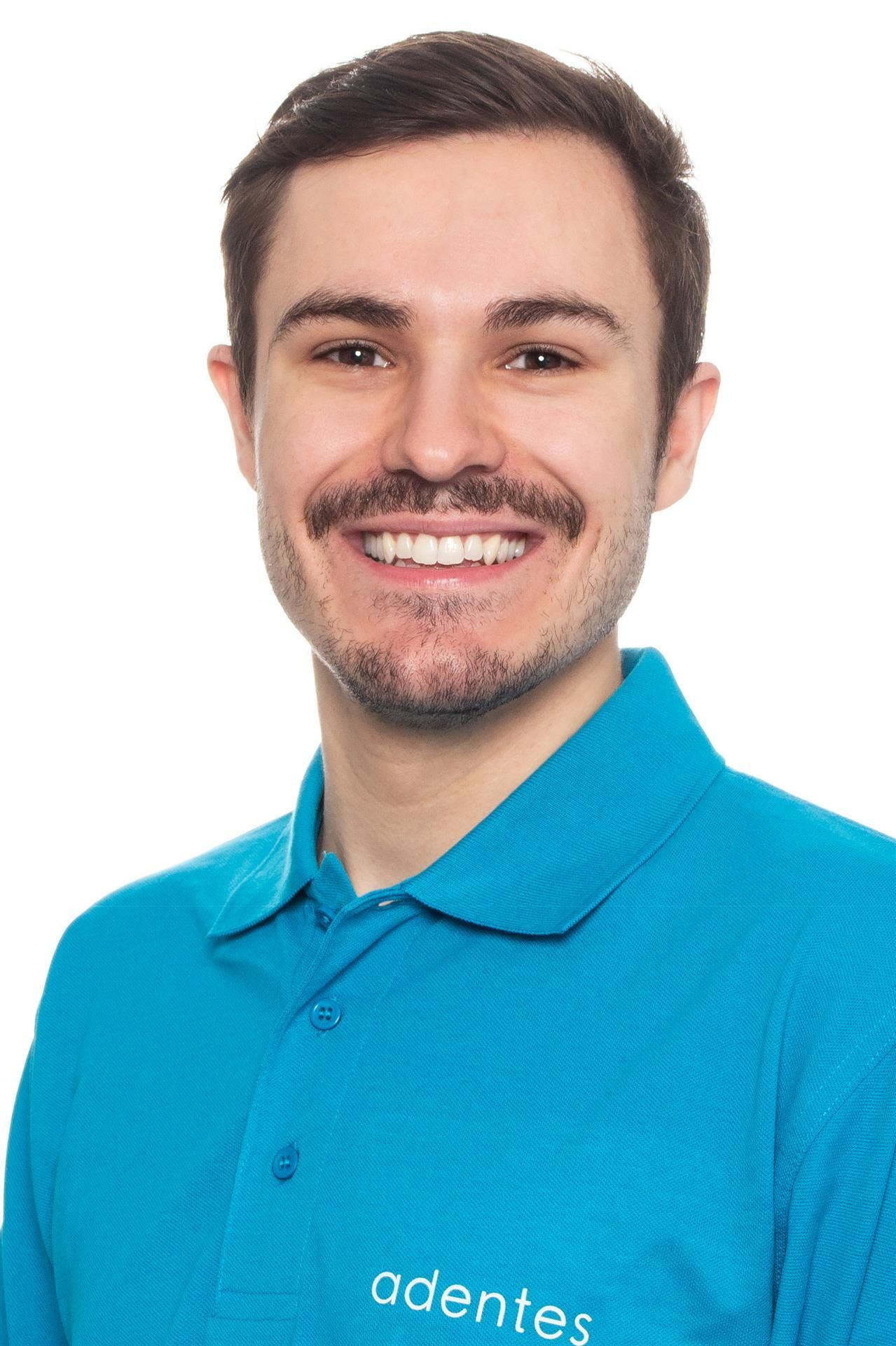 Zahnarzt Alexander Schäfer Ein Mann trägt ein blaues Poloshirt mit der Aufschrift „Adentes“