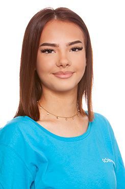 Assistenz Leonie Eine Frau mit Brille und blauem Hemd lächelt in die Kamera.