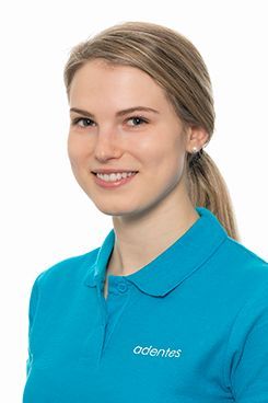 Dental Hygienist Jessica Eine Frau trägt ein blaues Poloshirt und lächelt.