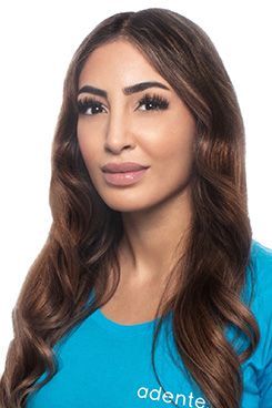 Rezeptionistin Ramona Eine Frau mit langen braunen Haaren trägt ein blaues Hemd.
