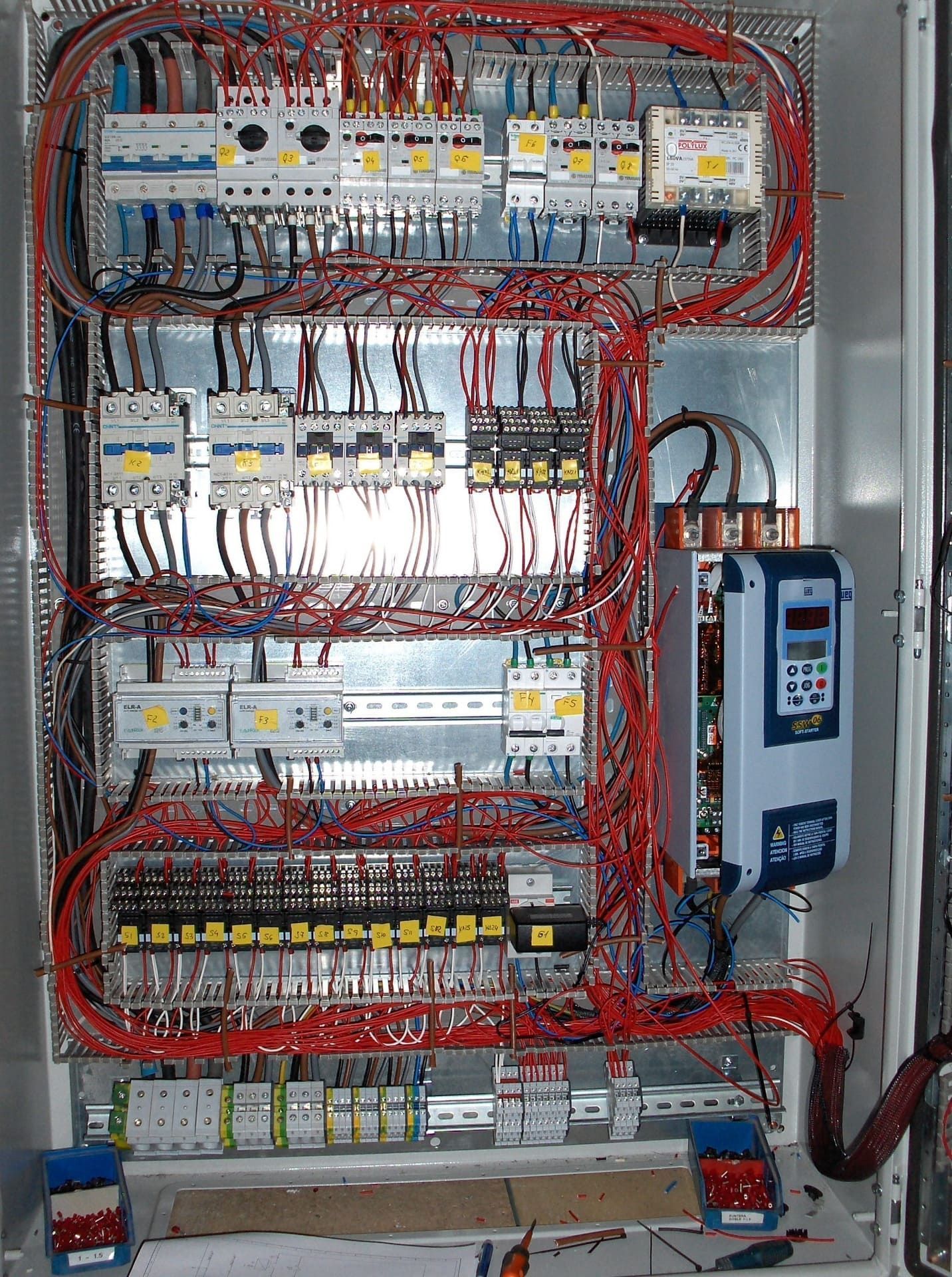 Panel de control con numerosos componentes eléctricos y cableado.