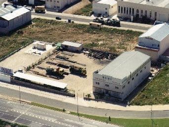 Vista aérea de una zona comercial con edificios, materiales de construcción y una calle.