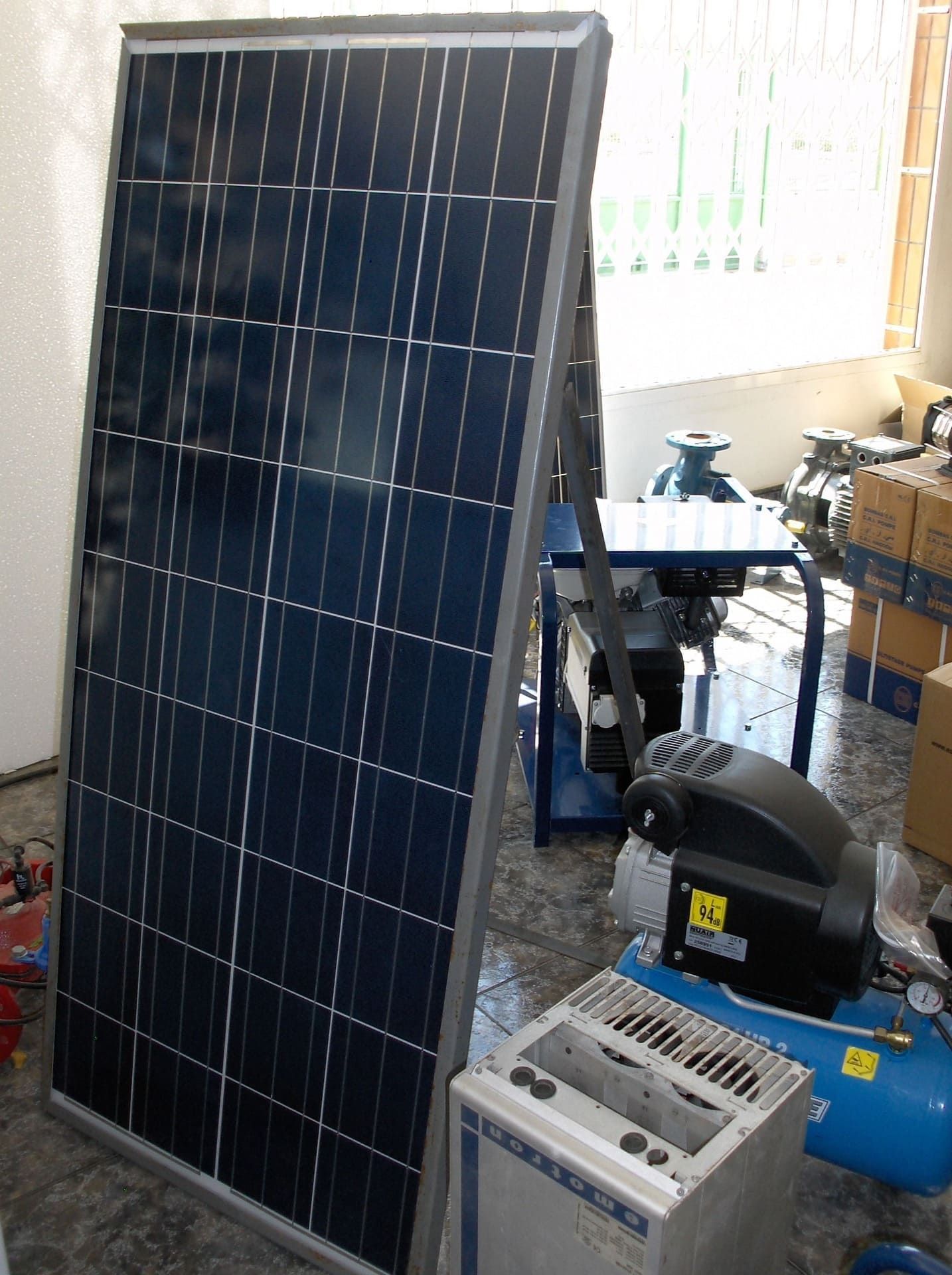 Panel solar instalado en el interior, cerca del compresor, el equipo y los tanques azules.