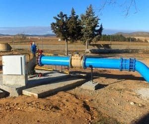 Tuberías y accesorios de agua azules en un entorno rural al aire libre.
