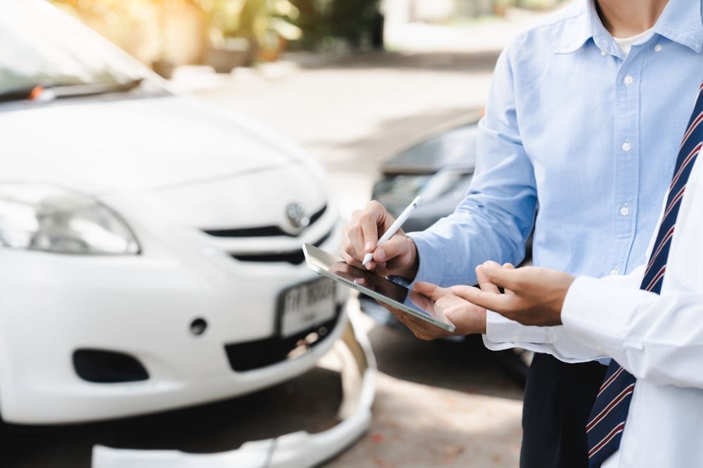 Dos personas revisan unos documentos junto a un coche blanco en un concesionario