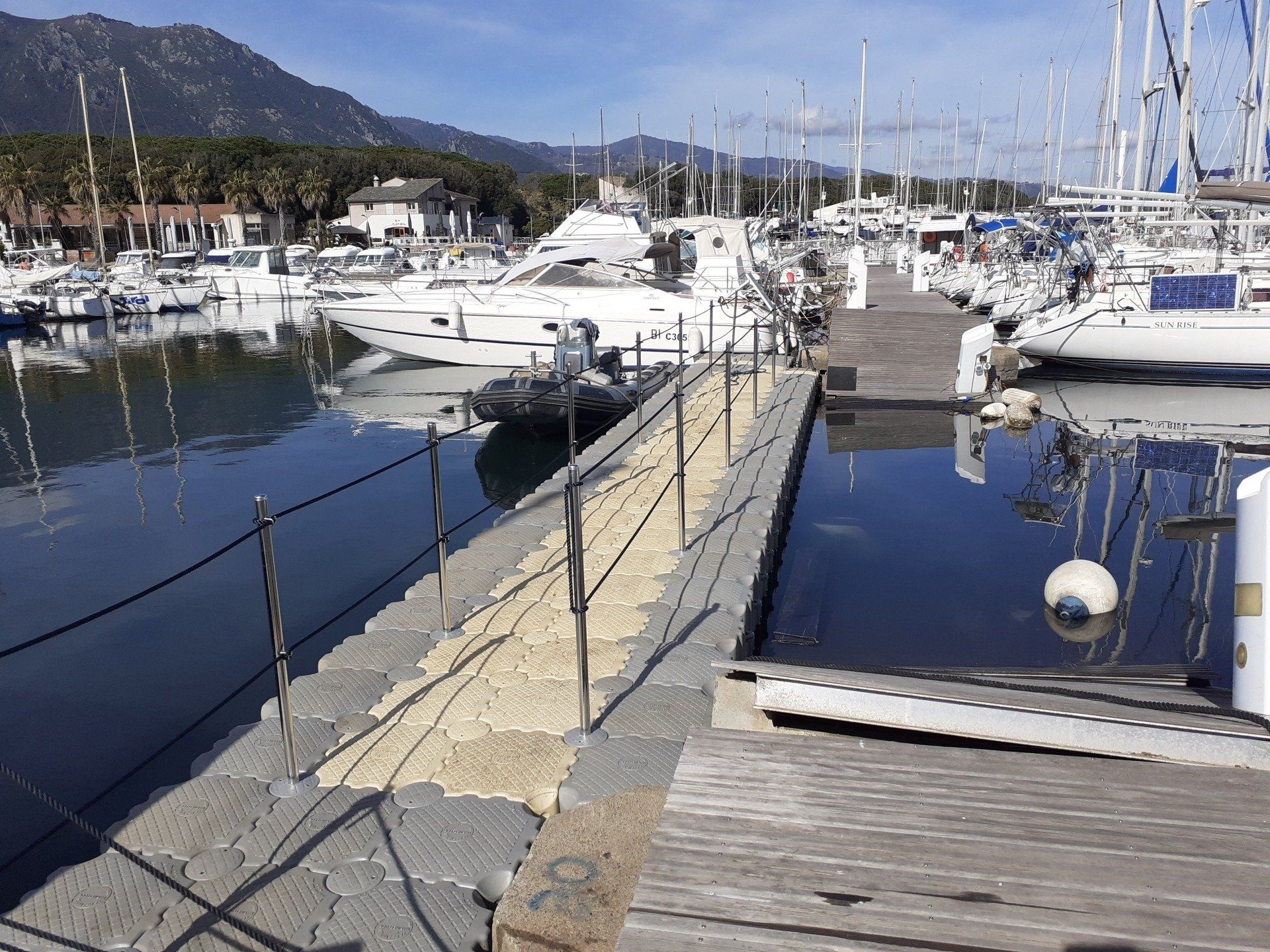 Un quai flottant mène aux bateaux amarrés dans une marina