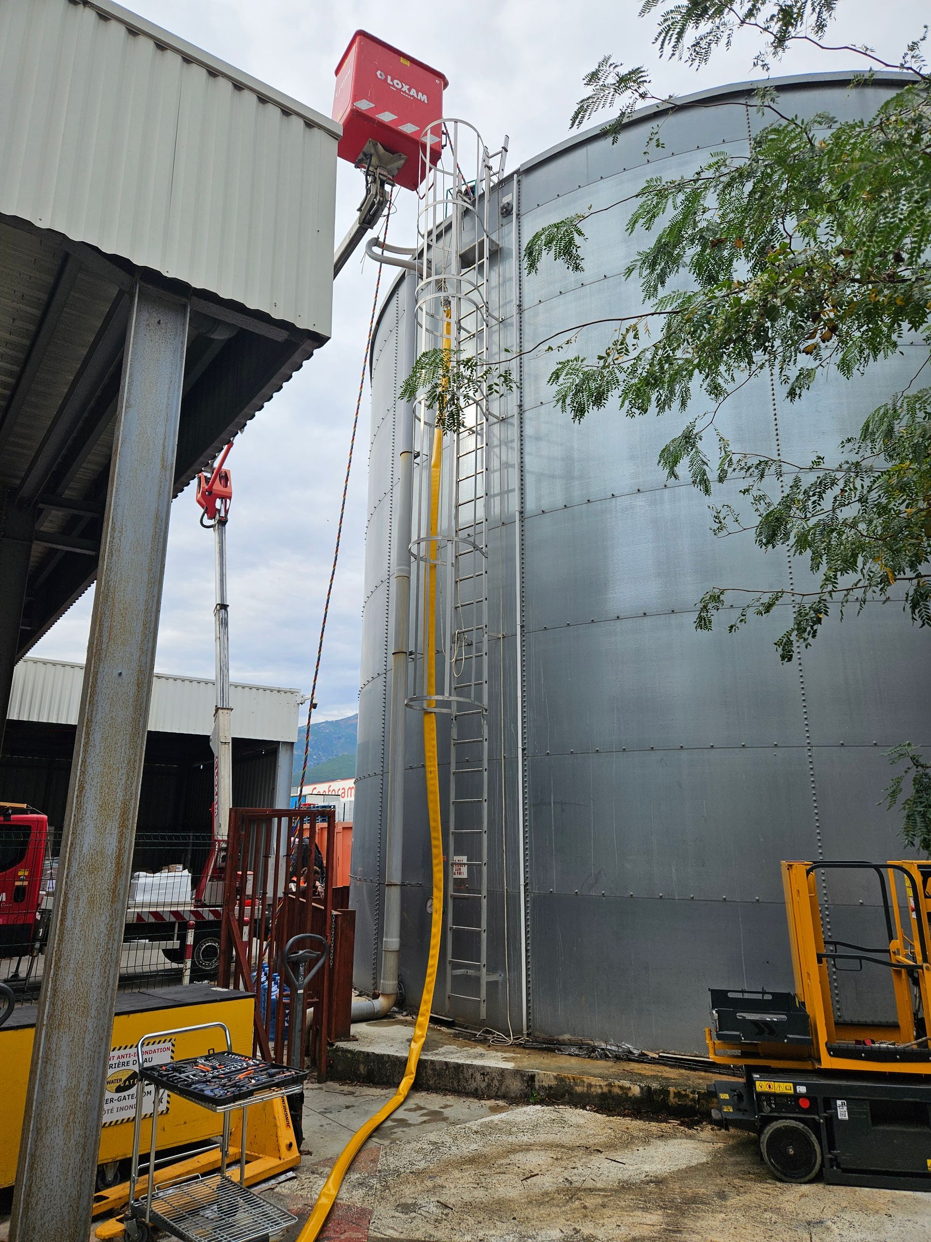 Grande cuve incendie avec échelle, équipement au sol et tuyau jaune