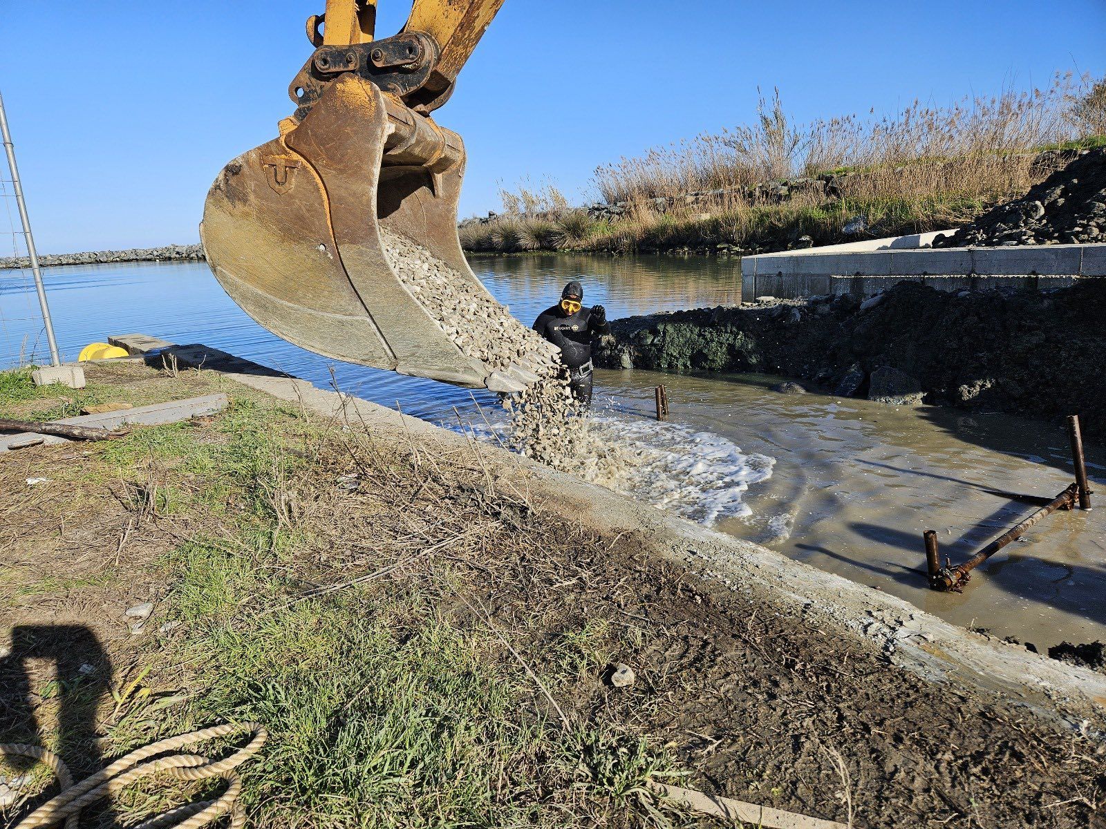 Une excavatrice déverse du gravier dans l'eau 