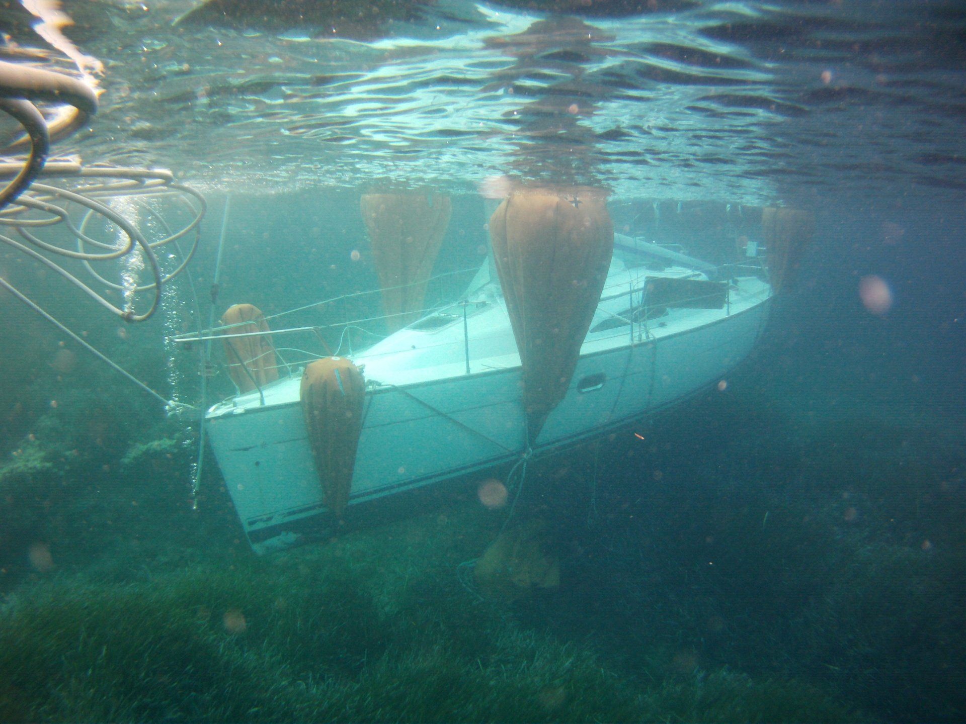 Vue sous-marine d'un voilier blanc partiellement immergé, porté par des flotteurs orange