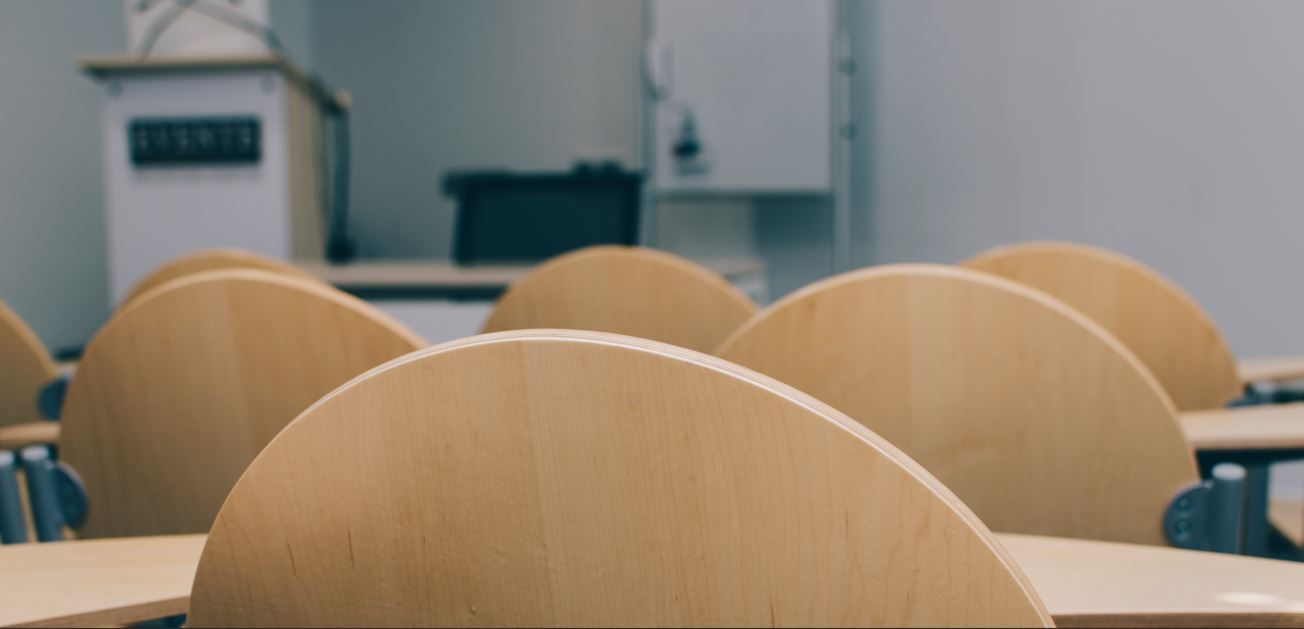 Trabajador de control de plagas con traje protector rociando el piso de una cocina, con insectos marrones cerca.