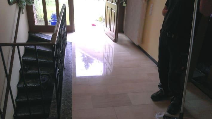 Eine Person steht in einem Flur mit Treppen und einem Wischmopp