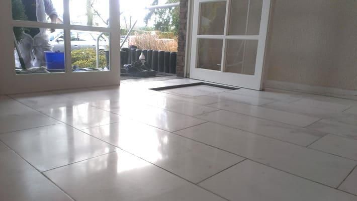 Ein Mann putzt in einem leeren Raum mit einem Wischmopp ein Fenster.